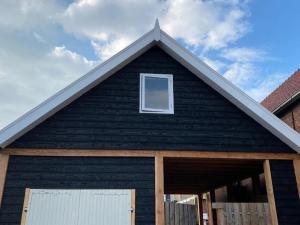 a black house with a gambrel roof at Tiny House Thuus in Sint Annaland