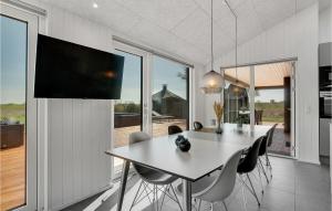 a dining room with a table and a television on a wall at Lovely Home In Ørsted With Wifi in Ørsted