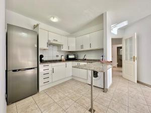 Una cocina con gabinetes blancos y un refrigerador de acero inoxidable. en Santiago Sun, en Puerto de Santiago