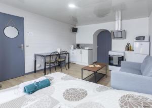 a living room with a bed and a table and a kitchen at LE COCON - T1 - 26 m2 in Lhommaizé