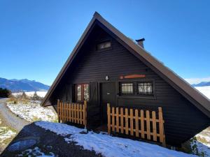 a black house with a fence in the snow at Chalet cosy 9 pers. avec balcon Sud, poêle à bois, Wi-Fi, proche pistes - Saint-Michel-de-Chaillol - FR-1-393-143 in Saint-Michel-de-Chaillol