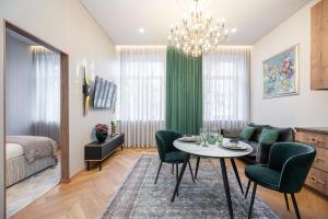 a living room with a table and green chairs at Poppy Apartments in Vilnius