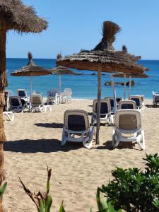a group of chairs and umbrellas on a beach at Casanoha in Fnidek