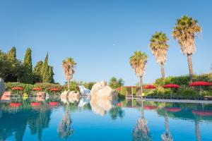 滨海阿热莱斯Camping Le Méditerranée Argelès - Domaine piétonnier的一个带红伞和棕榈树的水池