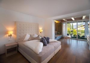 a bedroom with a large bed and a living room at Hotel Weingarten - Sankt Pauls - Eppan in Appiano sulla Strada del Vino