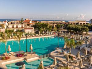 a large swimming pool with chairs and umbrellas at Porto Platanias Village Resort in Plataniás
