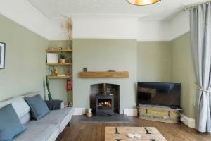 een woonkamer met een bank en een open haard bij Spacious House & Garden in Ilfracombe in Ilfracombe