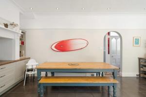 een keuken met een tafel en een rode surfplank aan de muur bij Spacious House & Garden in Ilfracombe in Ilfracombe +27 foto's