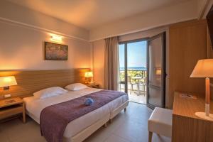 a hotel room with a bed and a balcony at Porto Platanias Village Resort in Plataniás +37 photos