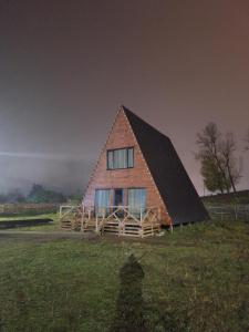 a large wooden house with a gambrel roof on a field at Mestia Sunrise Cottage - 3BR Mountain Retreat in Mestia
