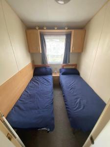 a small room with two beds and a window at seawick holiday park in Saint Osyth