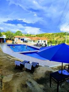 una grande piscina con panchine e ombrellone di Eco - Hotel San Miguel Barichara Campestre - Arte y café a Barichara