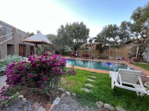a yard with a pool with a chair and flowers at Villa Djana Ouirgane in Ouirgane +26 photos
