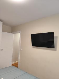 telewizor z płaskim ekranem wiszący na białej ścianie w obiekcie Piso recién reformado en Gascona w mieście Oviedo