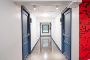 ein Flur mit blauen Türen und einer roten Wand in der Unterkunft Marwin Space in Bangkok