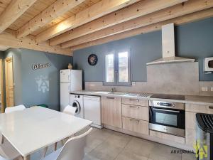 a kitchen with a table and a refrigerator and a stove at Chalet Caranne in Besse-et-Saint-Anastaise +2 photos