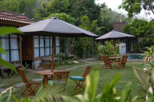a patio with tables and chairs and umbrellas at Shanti Life Wooden House in Pemuteran