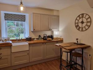 a kitchen with a sink and a clock on the wall at Stable Cottage in Arrochar