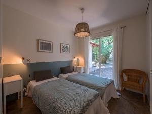 a bedroom with two beds and a table and a window at Villa Les Violettes à deux pas de la plage PYLA SUR MER in La Teste-de-Buch