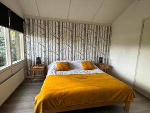 1 dormitorio con 1 cama con manta amarilla en Boshiem, en Bakkeveen