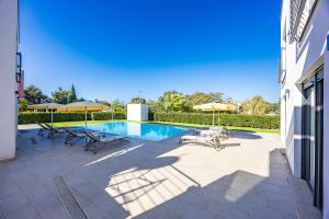 a swimming pool with chairs and umbrellas on a patio at Villa del Mar in Pula