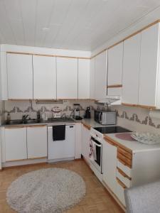 a kitchen with white cabinets and a rug at Hirvikoto in Sotkamo