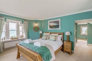 Un dormitorio con una cama grande con paredes azules. en Balcary Tower, en Castle Douglas