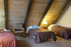 a attic room with two beds and a chair at Totorica Cabin in McCall