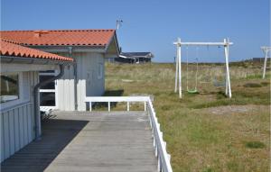 ein Holzsteg neben einem Gebäude mit einer Schaukel in der Unterkunft Four-Bedroom Holiday Home In Hvide Sande in Bjerregård
