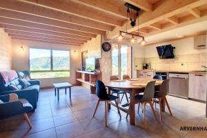 Una cocina y una sala de estar con mesa y sillas. en Lona Spa, en Chambon-sur-Lac
