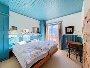 a blue bedroom with a large bed and a desk at Gaiola 2ème in Bagnes