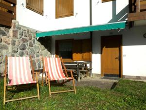 two chairs sitting in the grass outside of a building at Appartamento Bellavista in Cavalese