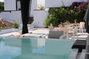 a swimming pool with chairs and a table and some water at Senhora do Carmo Charm House in Ponta Delgada