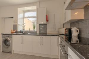Una cocina con gabinetes blancos y lavadora y secadora. en Chapel House, M65, Hospital, Good Parking, en Nelson 14 fotos más