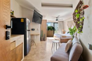 a room with a couch and a bed and a refrigerator at A Sweet Jungle Suite in Aldea Zama in Tulum