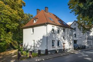 een wit gebouw met een rood dak op een straat bij Bibo City Apartment in Bielefeld