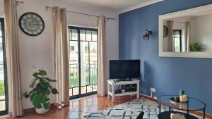sala de estar con TV y reloj en la pared en Apartamento Olhos do Mar, en Olhos de Água