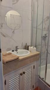 Un baño con lavabo y ducha con espejo. en Apartamento Olhos do Mar, en Olhos de Água 24 fotos más