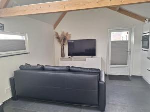 a living room with a black couch and a tv at Het Uitzicht in Malden