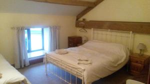 a bedroom with a large white bed and a window at Peers Clough Farm Cottage in Rossendale