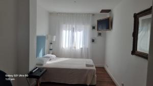 a white room with a bed and a window at The Coolest Place near the airport! in Lisbon