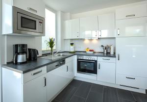 a white kitchen with white cabinets and a microwave at Leuchtturm 7 in Grossenbrode