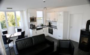 a kitchen with white cabinets and a living room with a couch at Leuchtturm 7 in Grossenbrode