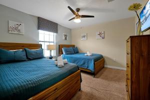 a bedroom with two beds and a ceiling fan at Embrace Disney Magic at Our Luxe 6-BR Villa in ChampionsGate! in Davenport