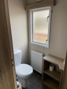 a small bathroom with a toilet and a window at The Lakeside 55 Caravan 8 Bert with Hot Tub at Tattershall Lakes in Tattershall