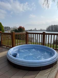 a hot tub on a deck with a view of the water at The Lakeside 55 Caravan 8 Bert with Hot Tub at Tattershall Lakes in Tattershall