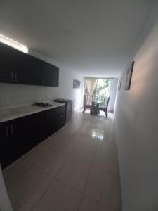 a kitchen with white walls and black cabinets and a table at Apartaestudios amoblados el caney in Cali +10 photos