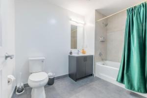 e bagno con servizi igienici bianchi e tenda doccia verde. di 2 bedroom 2 bath Suite, Near American Dream and The Airport, Free Parking, King Bed and 2 Queen Beds, Washer and Dryer a Orange