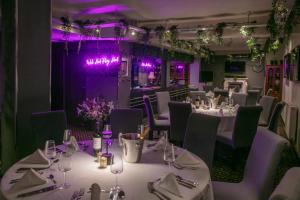 ein Esszimmer mit Tischen und Stühlen und violetter Beleuchtung in der Unterkunft Best Western Glasgow Hotel in Glasgow