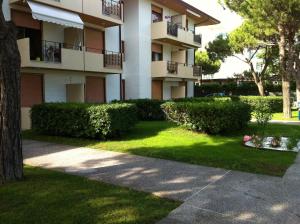 a building with bushes and a sidewalk in front of it at RESIDENCE GARDEN -WALTERIGATO Apartments SOLO PER FAMIGLIE in Lido di Jesolo
